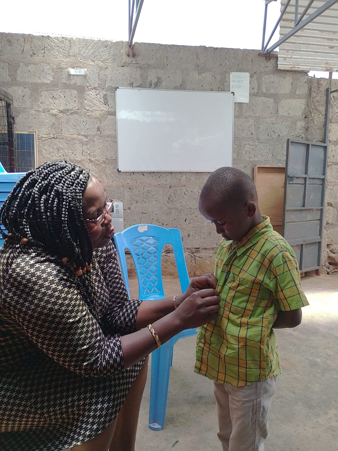 Mentor helping a young boy with his shirt